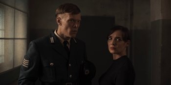 Movie still from “Dark” (2017), created by Baran bo Odar – A man and a woman standing next to each other; Medium shot, Low angle