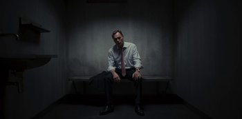 Movie still from “Dark” (2017), created by Baran bo Odar – A man sitting on top of a bench wearing a tie; Medium shot, High angle