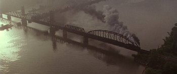 Movie still from “Biloxi Blues” (1988), directed by Mike Nichols – A train bridge with smoke billowing out of it; Extreme Wide shot, High angle