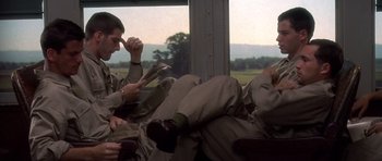 Movie still from “Biloxi Blues” (1988), directed by Mike Nichols – Two men sitting on a train looking at their cell phones; Medium shot, Over the shoulder angle