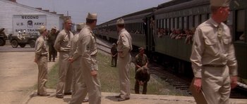 Movie still from “Biloxi Blues” (1988), directed by Mike Nichols – A group of men standing next to each other near train tracks; Wide shot, High angle