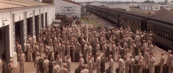 Movie still from “Biloxi Blues” (1988), directed by Mike Nichols – A large group of men standing next to each other on a sidewalk; Extreme Wide shot, High angle