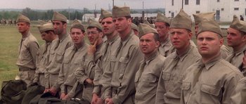 Movie still from “Biloxi Blues” (1988), directed by Mike Nichols – A group of men standing next to each other in uniform; Medium shot, Over the shoulder angle