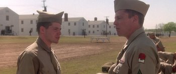 Movie still from “Biloxi Blues” (1988), directed by Mike Nichols – Two men in military uniforms are standing in a field; Medium shot, Over the shoulder angle