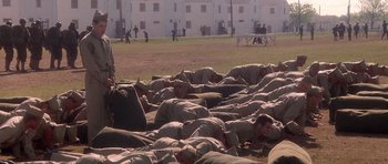 Movie still from “Biloxi Blues” (1988), directed by Mike Nichols – A number of people laying on the ground in a field; Wide shot, High angle