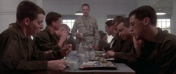 Movie still from “Biloxi Blues” (1988), directed by Mike Nichols – A group of men sitting at a table eating food; Medium shot, Low angle