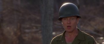 Movie still from “Biloxi Blues” (1988), directed by Mike Nichols – A man wearing a military helmet in the woods; Close Up shot, Over the shoulder angle