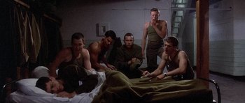 Movie still from “Biloxi Blues” (1988), directed by Mike Nichols – A group of men sitting on top of a bed next to each other; Wide shot, High angle