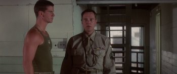 Movie still from “Biloxi Blues” (1988), directed by Mike Nichols – A man in a uniform standing next to another man; Medium shot, Low angle