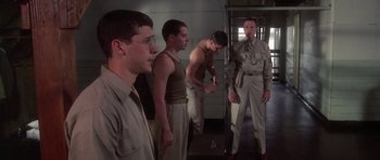 Movie still from “Biloxi Blues” (1988), directed by Mike Nichols – A group of men standing next to each other in a room; Wide shot, Over the shoulder angle