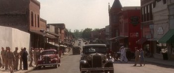 Movie still from “Biloxi Blues” (1988), directed by Mike Nichols – An old fashioned car drives down the street; Extreme Wide shot, High angle