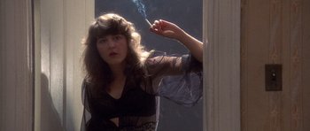 Movie still from “Biloxi Blues” (1988), directed by Mike Nichols – A woman smoking a cigarette in front of a mirror; Medium shot, Low angle