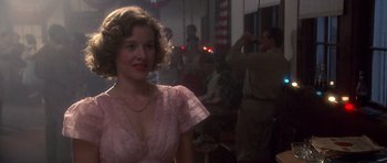 Movie still from “Biloxi Blues” (1988), directed by Mike Nichols – A woman in a pink dress standing in front of a crowd; Close Up shot, Over the shoulder angle