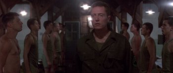 Movie still from “Biloxi Blues” (1988), directed by Mike Nichols – A man standing in front of a group of people; Medium shot, Over the shoulder angle