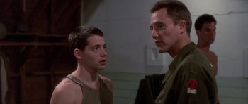 Movie still from “Biloxi Blues” (1988), directed by Mike Nichols – A man standing next to another man in a room; Close Up shot, Over the shoulder angle