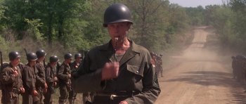 Movie still from “Biloxi Blues” (1988), directed by Mike Nichols – A man in a military uniform smoking a cigarette; Medium shot, Over the shoulder angle