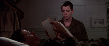 Movie still from “Biloxi Blues” (1988), directed by Mike Nichols – A young man reading a book while another man watches; Close Up shot, Over the shoulder angle