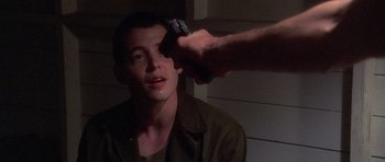 Movie still from “Biloxi Blues” (1988), directed by Mike Nichols – A man holding a handgun up to a man's face; Close Up shot, Over the shoulder angle