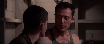 Movie still from “Biloxi Blues” (1988), directed by Mike Nichols – A man in a tank top talking to another man in a green tank top; Close Up shot, Over the shoulder angle