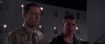 Movie still from “Biloxi Blues” (1988), directed by Mike Nichols – A couple of men standing next to each other in the rain; Close Up shot, Low angle