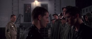 Movie still from “Biloxi Blues” (1988), directed by Mike Nichols – A group of men standing around a man in a black shirt; Medium shot, Over the shoulder angle