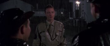 Movie still from “Biloxi Blues” (1988), directed by Mike Nichols – A man in a uniform standing in the pouring rain; Medium shot, Over the shoulder angle