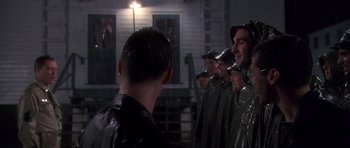 Movie still from “Biloxi Blues” (1988), directed by Mike Nichols – A group of men standing next to each other in the rain; Medium shot, Over the shoulder angle
