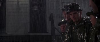 Movie still from “Biloxi Blues” (1988), directed by Mike Nichols – A group of people standing in the rain; Medium shot, Over the shoulder angle