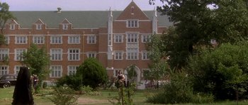 Movie still from “Biloxi Blues” (1988), directed by Mike Nichols – A large brick building in the middle of a green field; Extreme Wide shot, Low angle