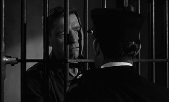 Movie still from “Birdman of Alcatraz” (1962), directed by John Frankenheimer – A man in a jail cell talking to a man in a uniform; Medium shot, Low angle