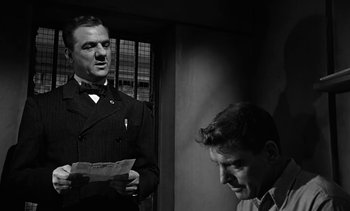 Movie still from “Birdman of Alcatraz” (1962), directed by John Frankenheimer – Two men are standing next to each other and one is holding a piece of paper in his hand; Close Up shot, Low angle