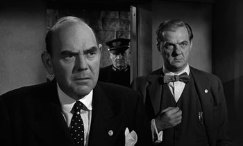 Movie still from “Birdman of Alcatraz” (1962), directed by John Frankenheimer – A group of men standing next to each other in a room; Medium shot, Low angle