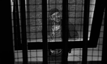 Movie still from “Birdman of Alcatraz” (1962), directed by John Frankenheimer – A black and white photo of a man looking through bars; Medium shot, Overhead angle