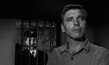 Movie still from “Birdman of Alcatraz” (1962), directed by John Frankenheimer – A man standing in front of a jail cell with another man behind bars; Close Up shot, Low angle