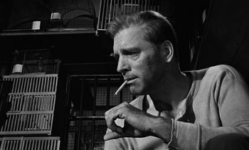 Movie still from “Birdman of Alcatraz” (1962), directed by John Frankenheimer – A black and white photo of a man smoking a cigarette; Close Up shot, Low angle