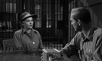 Movie still from “Birdman of Alcatraz” (1962), directed by John Frankenheimer – An old photo of a man and a woman sitting at a table in front of a jail cell; Medium shot, Over the shoulder angle