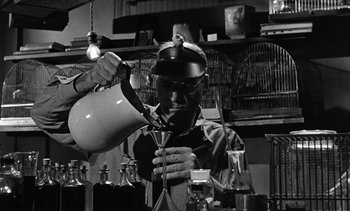 Movie still from “Birdman of Alcatraz” (1962), directed by John Frankenheimer – A man pouring liquid into a pitcher in a lab; Medium shot, Low angle