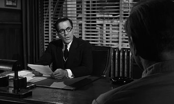 Movie still from “Birdman of Alcatraz” (1962), directed by John Frankenheimer – A man sitting at a table in front of another man; Medium shot, Over the shoulder angle