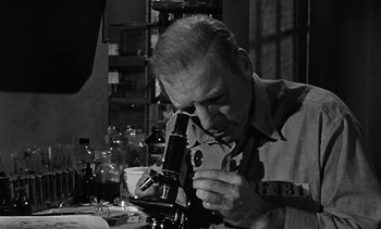 Movie still from “Birdman of Alcatraz” (1962), directed by John Frankenheimer – An older man looking through a microscope in a room; Close Up shot, High angle