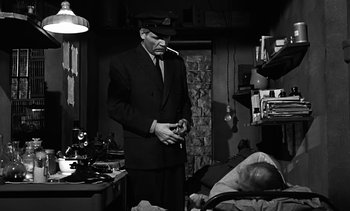 Movie still from “Birdman of Alcatraz” (1962), directed by John Frankenheimer – A black and white photo of a man smoking a cigarette; Medium shot, Over the shoulder angle
