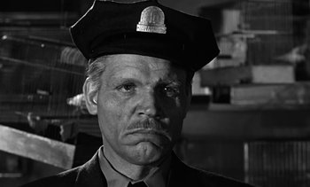 Movie still from “Birdman of Alcatraz” (1962), directed by John Frankenheimer – An old man wearing a police uniform and a hat; Close Up shot, Low angle