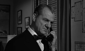 Movie still from “Birdman of Alcatraz” (1962), directed by John Frankenheimer – An older man talking on a phone while wearing a bow tie; Close Up shot, Low angle
