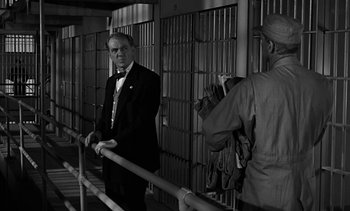 Movie still from “Birdman of Alcatraz” (1962), directed by John Frankenheimer – A man standing next to another man in a jail cell; Medium shot, Over the shoulder angle