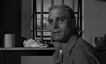Movie still from “Birdman of Alcatraz” (1962), directed by John Frankenheimer – An older man wearing glasses sitting in front of a window; Close Up shot, Over the shoulder angle