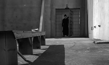 Movie still from “Birdman of Alcatraz” (1962), directed by John Frankenheimer – A man standing in front of an open gate; Wide shot, High angle