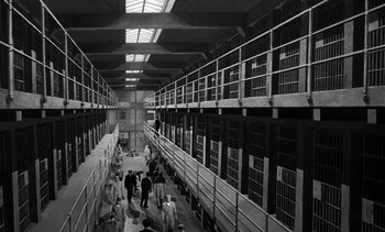 Movie still from “Birdman of Alcatraz” (1962), directed by John Frankenheimer – A group of people standing inside of a jail cell; Extreme Wide shot, High angle