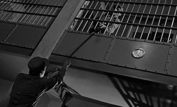 Movie still from “Birdman of Alcatraz” (1962), directed by John Frankenheimer – A man standing in front of a jail cell; Medium shot, Low angle