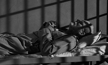 Movie still from “Birdman of Alcatraz” (1962), directed by John Frankenheimer – A man laying on a bed in a jail cell; Medium shot, High angle