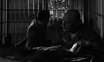 Movie still from “Birdman of Alcatraz” (1962), directed by John Frankenheimer – Two men sitting on a bed next to a jail cell; Medium shot, Over the shoulder angle