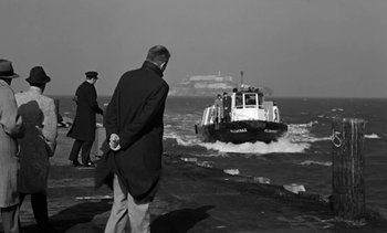 Movie still from “Birdman of Alcatraz” (1962), directed by John Frankenheimer – A man standing next to a boat in the water; Wide shot, Low angle